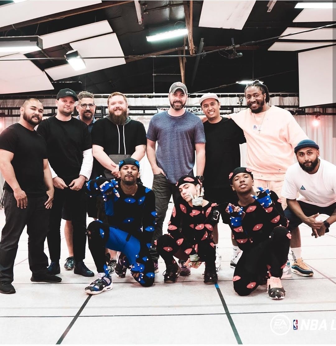 Taiwan Williams kneeling in a blue motion capture suit with the mocap crew on the volume stage