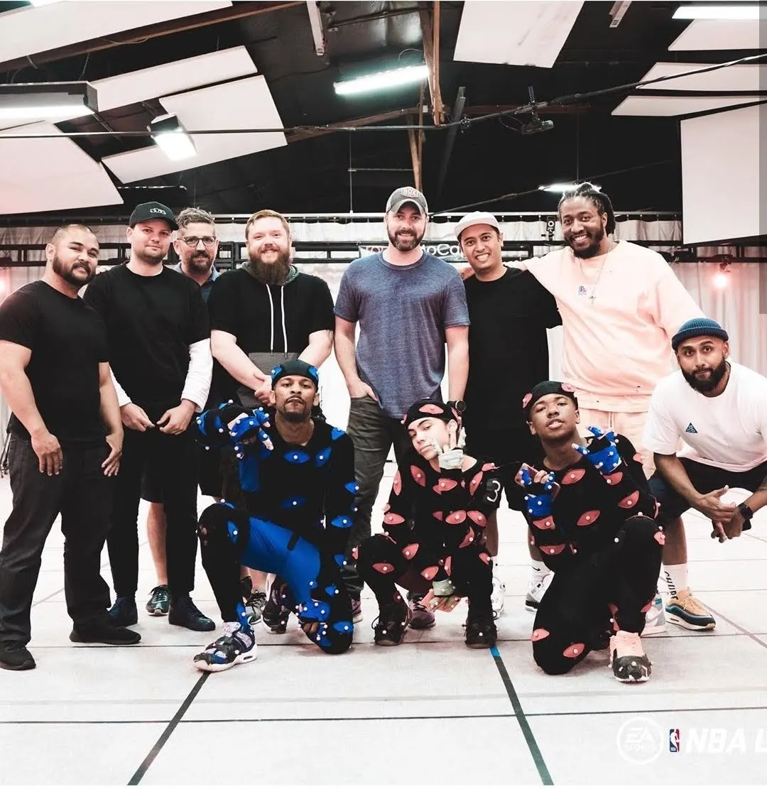 Taiwan Williams kneeling in a blue motion capture suit with the mocap crew on the volume stage